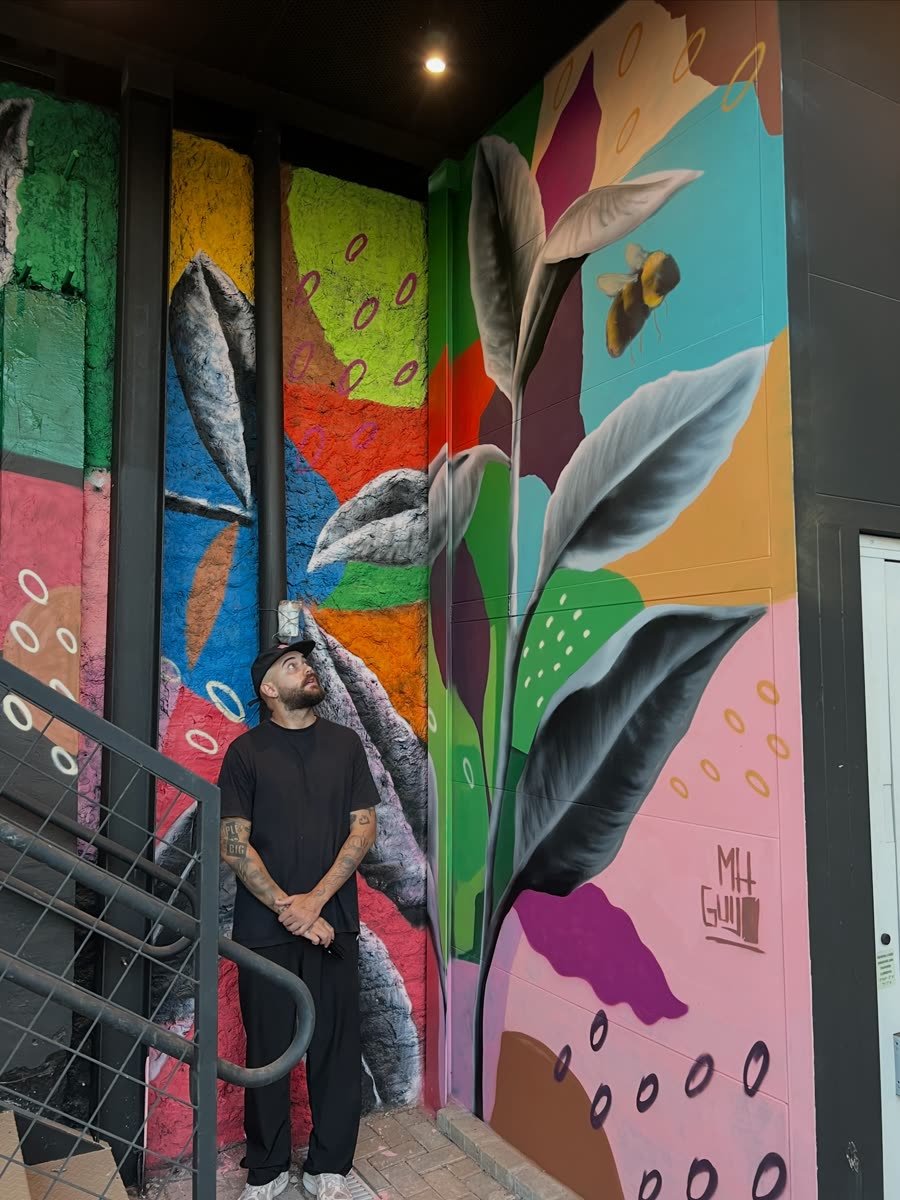 Eu em frente a uma parede de flores e folhas coloridas